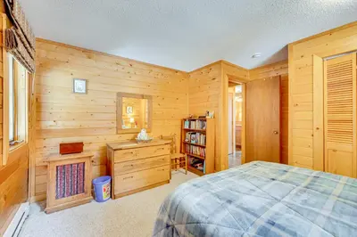 a bedroom with a bed and a wooden wall at 4 Mi to RMNP Allenspark Cabin with Wraparound Deck! in Allenspark