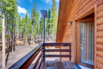 a wooden deck with a door and trees in the background at 4 Mi to RMNP Allenspark Cabin with Wraparound Deck! in Allenspark