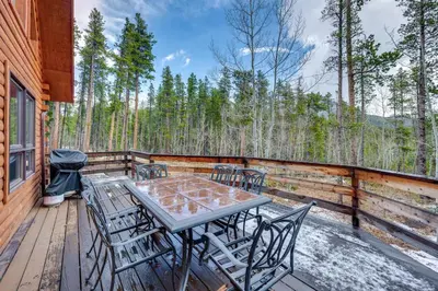a wooden deck with a table and chairs on it at 4 Mi to RMNP Allenspark Cabin with Wraparound Deck! in Allenspark