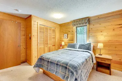 a bedroom with a bed and a wooden wall at 4 Mi to RMNP Allenspark Cabin with Wraparound Deck! in Allenspark