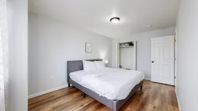 a white bedroom with a large bed and wooden floors at Great Two King Bed Rooms Near Airport Ideal Stay in Brighton
