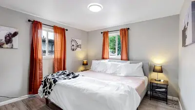 a bedroom with a large white bed with orange curtains at Arvada Private Family Home with Two King Beds in Arvada