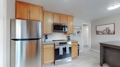 a kitchen with a stainless steel refrigerator and wooden cabinets at Arvada Private Family Home with Two King Beds in Arvada