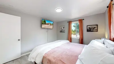 a bedroom with a bed with white sheets and a window at Arvada Private Family Home with Two King Beds in Arvada