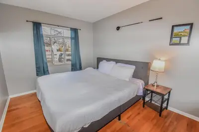 a bedroom with a large white bed and a window at Family Home with Large Yard & Golf Theme Near Rail in Denver