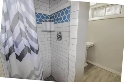 a bathroom with a shower with blue and white tiles at Family Home with Large Yard & Golf Theme Near Rail in Denver