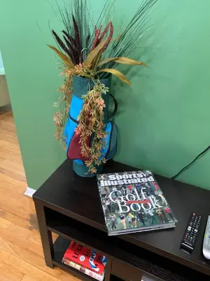 a table with a book and a vase with a plant at Family Home with Large Yard & Golf Theme Near Rail in Denver