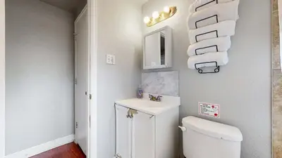 a bathroom with a toilet and a sink and towels at Cool Stay Near Rapids Stadium Ideal for Sports Fans in Commerce City