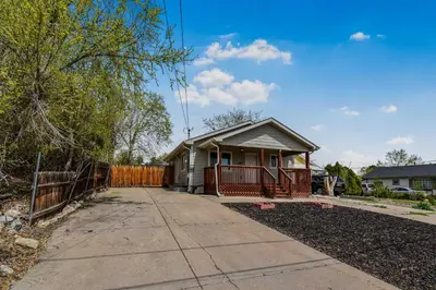a house with a fence next to a driveway at Fun and Affordable Dual Bedroom Lower Unit in Vibrant Denver in Denver