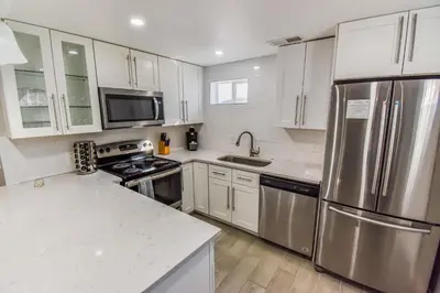 a kitchen with white cabinets and stainless steel appliances at Vibrant & Cozy Two Bedroom Lower Unit King Beds in Denver