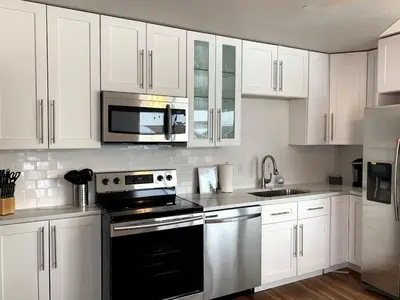 a kitchen with white cabinets and a black stove top oven at Family Friendly & Cozy Two Bedroom Denver in Denver