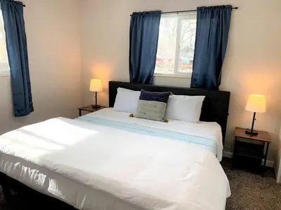 a bedroom with a large white bed with blue curtains at Family Friendly & Cozy Two Bedroom Denver in Denver