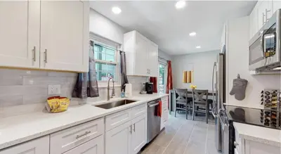 a kitchen with white cabinets and a sink and a table at Updated Family Unit with Two King Beds in Denver