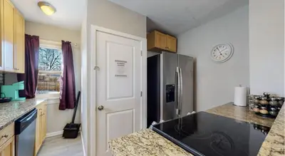 a kitchen with a refrigerator and a clock on the wall at Cozy upper unit great for family visiting Zoo medica campus and downtown in Denver