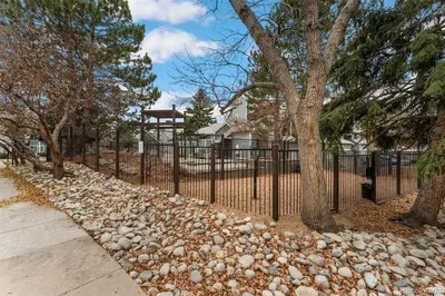 a fence with a bunch of rocks next to trees at Updated Two-Bedroom with Three King Beds Loft & Two Baths in Aurora
