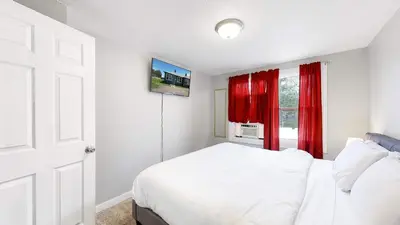 a bedroom with a bed and a window with red curtains at Cozy King Bed Hideaway Near Top Concerts & Sports in Commerce City