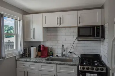 a kitchen with white cabinets and a sink and a microwave at Great Updated King Bed Near Denver Sports field and concerts in Commerce City