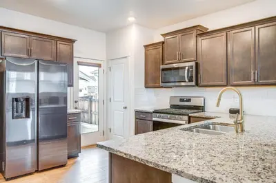 a kitchen with stainless steel appliances and wooden cabinets at Perfect for Families! Quiet Aurora Home in Aurora