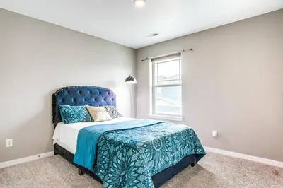 a bedroom with a bed with a blue headboard and a window at Perfect for Families! Quiet Aurora Home in Aurora