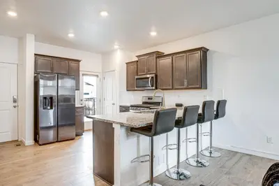 a kitchen with wooden cabinets and a counter with bar stools at Perfect for Families! Quiet Aurora Home in Aurora