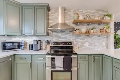 a kitchen with green cabinets and a stove top oven at Charming Central Denver Bungalow With Hot Tub in Denver