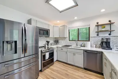 a kitchen with stainless steel appliances and white cabinets at Urban Oasis in the Heart of Denver with Hot tub in Denver