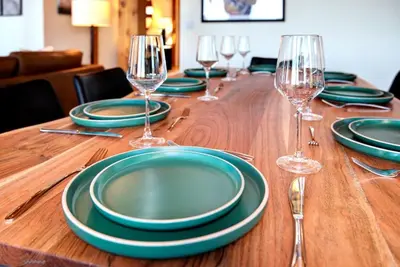 a wooden table with green plates and wine glasses at Mountain Retreat Sleeps 10 with Pool Table and Arcade in Littleton