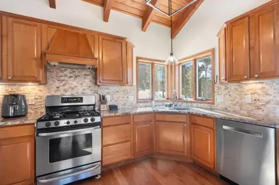 a kitchen with wooden cabinets and stainless steel appliances at Mountain Retreat Sleeps 10 with Pool Table and Arcade in Littleton