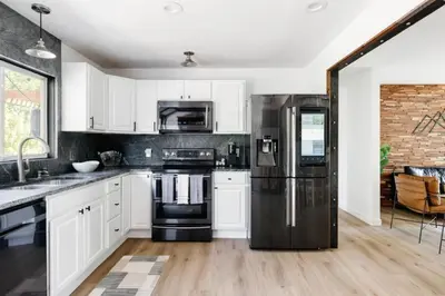 a kitchen with white cabinets and a black refrigerator at 5 Star Retreat With A Gym And APrivate Office in Thornton