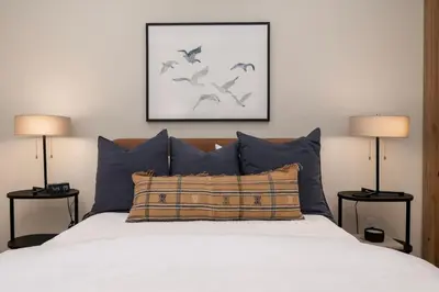 a bedroom with a bed with blue pillows and two lamps at Downtown Fraser with Hot Tub in Fraser