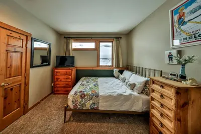 a bedroom with a bed and a dresser and a television at Rocky Mountain Retreat Steps to Slopes with Hot Tub and Spectacular Views in Winter Park