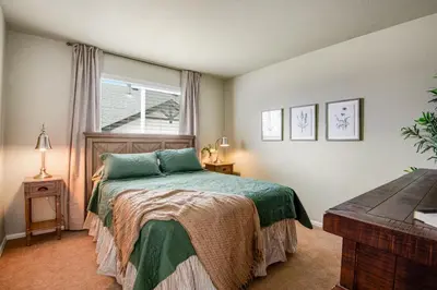 a bedroom with a bed with a green bedspread and a window at 5 bed 4 bath and Pet friendly in Erie