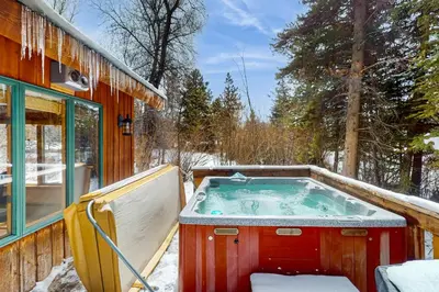 a hot tub sitting outside of a house in the snow at Blue Riverfront Retreat in Silverthorne