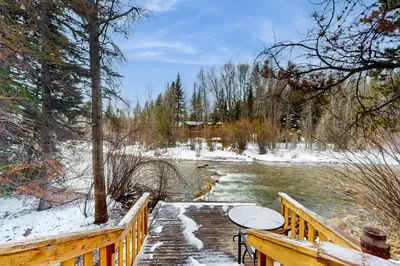 a wooden bridge over a river in the snow at Blue Riverfront Retreat in Silverthorne