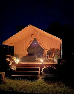 a tent with a chair in a field at night at Colorado Getaways in this Lovely Safari Tent on Working Sheep Farm in Longmont in Longmont