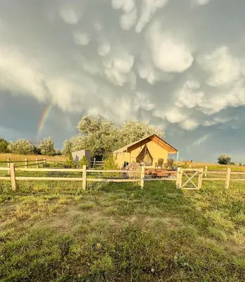 a rainbow in the sky over a field with a barn at Colorado Getaways in this Lovely Safari Tent on Working Sheep Farm in Longmont in Longmont