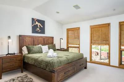 a bedroom with a bed with a wooden headboard and windows at 5 Bedroom Whole Home with Mountain Views in Evergreen