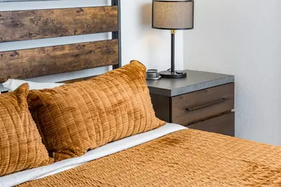 a bed with an orange blanket and a lamp on a night stand at 5 Bedroom Whole Home with Mountain Views in Evergreen