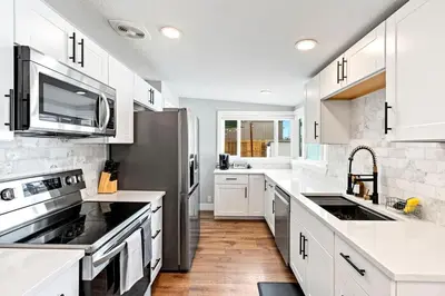 a kitchen with white cabinets and a stainless steel refrigerator at 5Bed, 2Bath, 2 Kitchens, Home Office, Pet-Friendly in Denver
