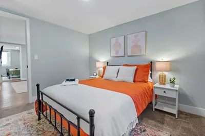 a bedroom with a large bed with an orange blanket at 5Bed, 2Bath, 2 Kitchens, Home Office, Pet-Friendly in Denver