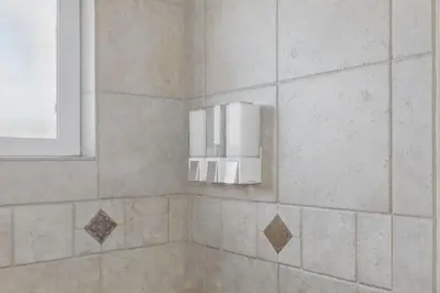 a bathroom with a shower with a light on the wall at Spacious 4BD - Backyard BBQ, Fire Pit & Mini Golf in Arvada