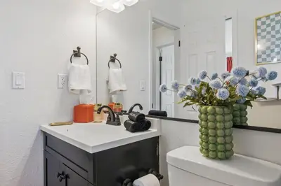 a bathroom with a sink and a vase of flowers on a toilet at Spacious 4BD - Backyard BBQ, Fire Pit & Mini Golf in Arvada