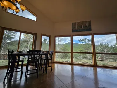 a dining room with a table and chairs and large windows at Moose Manor in Golden