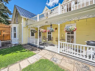 a yellow house with white railings and a porch at Charming Downtown Apartment in Victorian Home with Mountain Views in Georgetown