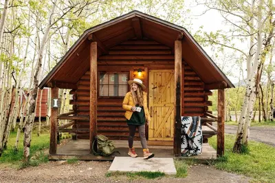 a woman standing in front of a small cabin at Colorado Glamping Adventures in Golden Gate Canyon Park, in this Cute Cabin Rental in Black Hawk
