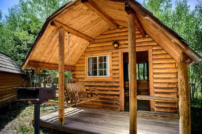 a log cabin with a porch and a grill at Colorado Glamping Adventures in Golden Gate Canyon Park, in this Cute Cabin Rental in Black Hawk