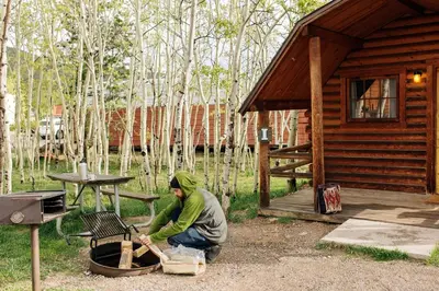 a man is chopping wood in front of a cabin at Colorado Glamping Adventures in Golden Gate Canyon Park, in this Cute Cabin Rental in Black Hawk