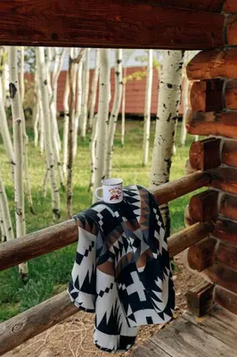 a sweater and a cup on a wooden fence at Colorado Glamping Adventures in Golden Gate Canyon Park, in this Cute Cabin Rental in Black Hawk