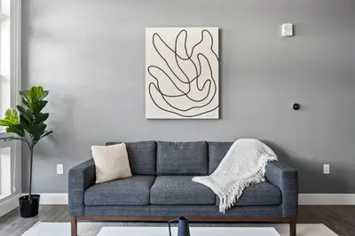 a living room with a gray couch and a painting at Mile High Muse Lifestyle Loft Espadin LoHi in Denver