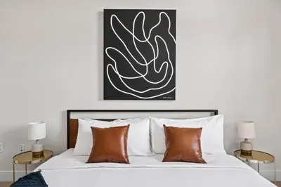 a bedroom with a bed with white sheets and brown pillows at Mile High Muse Lifestyle Loft Espadin LoHi in Denver